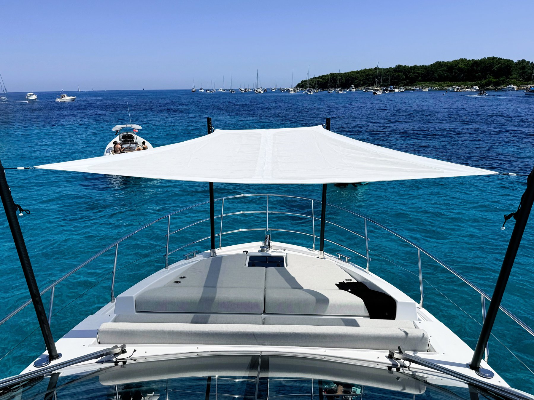 Bow sun loungers under the shade sail, anchored in turquoise water